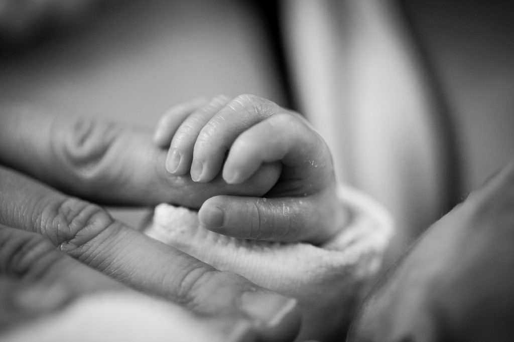 un bébé qui tient la main de sa maman